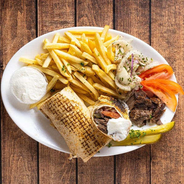 Shawarmaz Mediterranean Restaurant & Grill's shawarma plate with fries, sliced tomatoes, onions, and pickles.