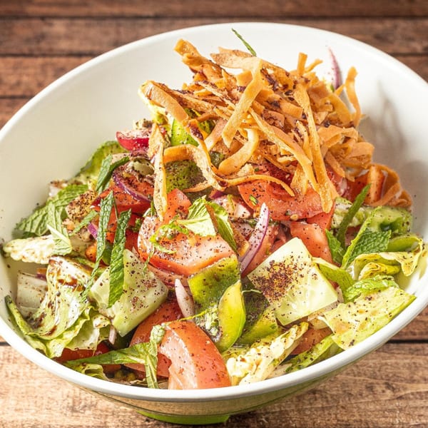 Close-up of a vibrant Fattoush salad with lettuce, tomatoes, cucumbers, mint, and crispy pita.